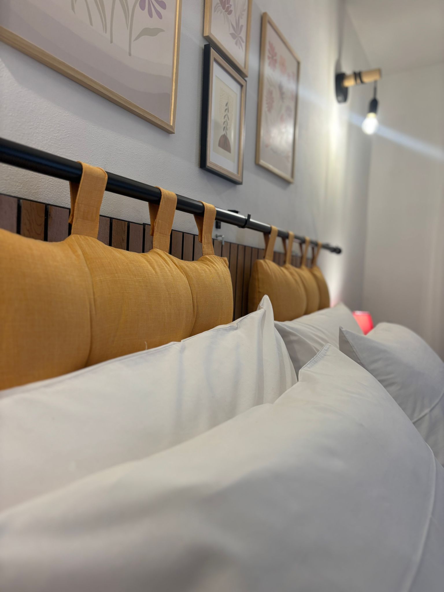 Testiera del letto con cuscini ocra e quadri floreali